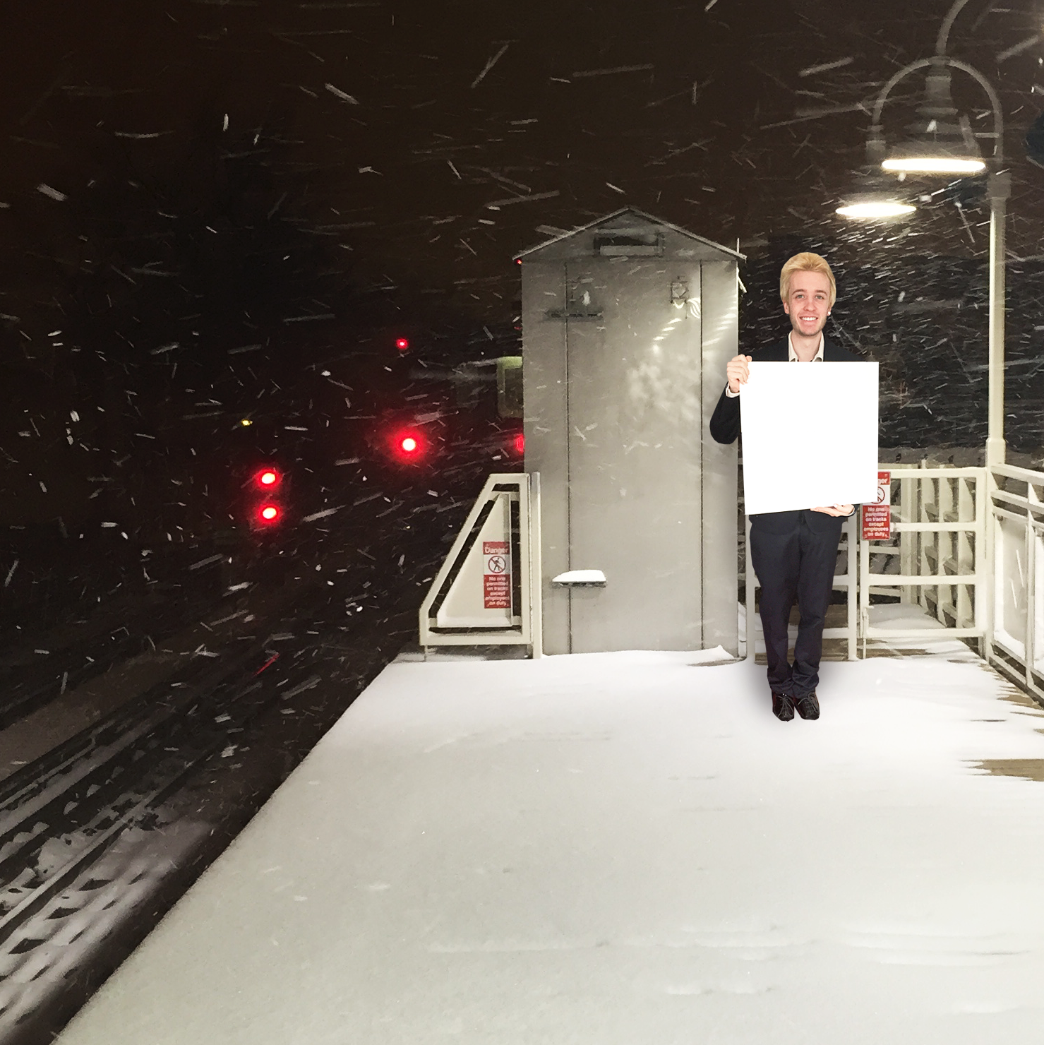 Butler holding a blank sign on a train platform in the snow